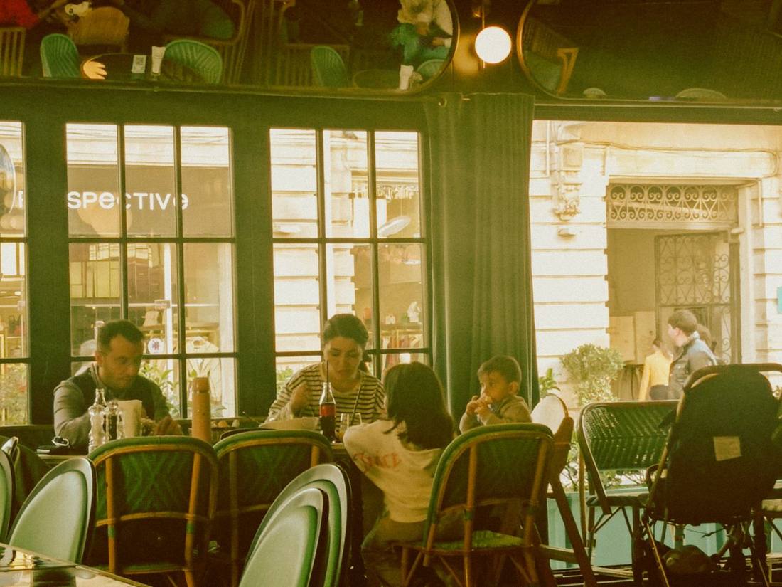 Old café interior with bentwood chairs, tall windows and guests at marble tables