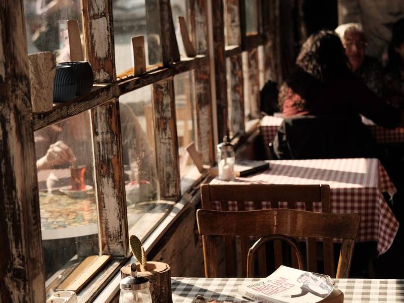 Guests at a checkered-cloth table beside a sunlit café window