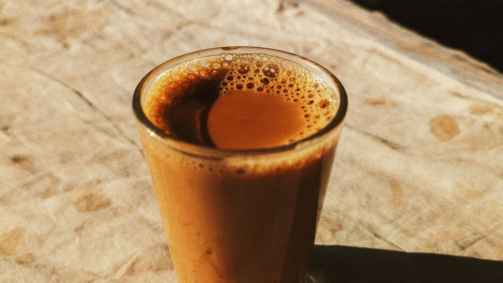 A glass of Irani chai on a sunlit wooden café table