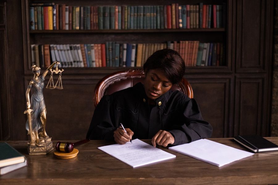 A judge settling papers at a desk lined with law reports