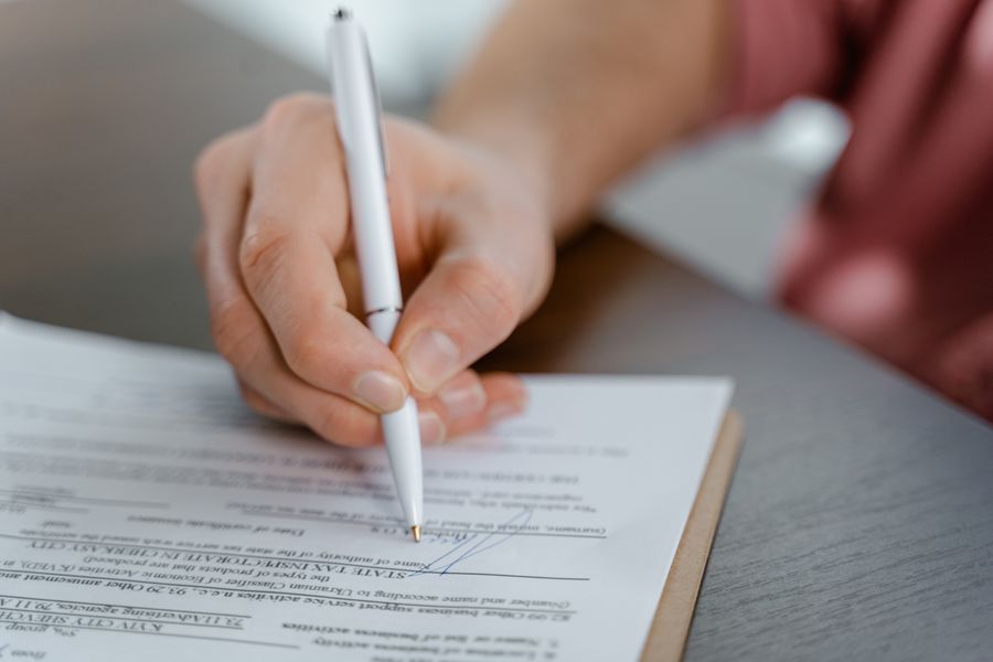 A hand signing a property document with a pen