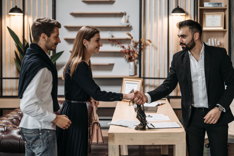 Parties shaking hands across a table after a mediated settlement