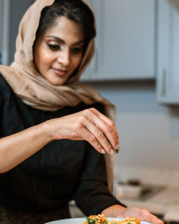 Indian woman chef in a headscarf plating a dish