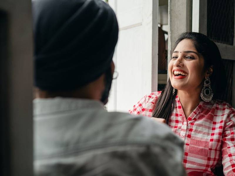 Indian woman in a checked shirt laughing across a café table