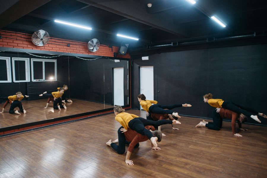 Dancers rehearsing contemporary choreography in a mirrored studio