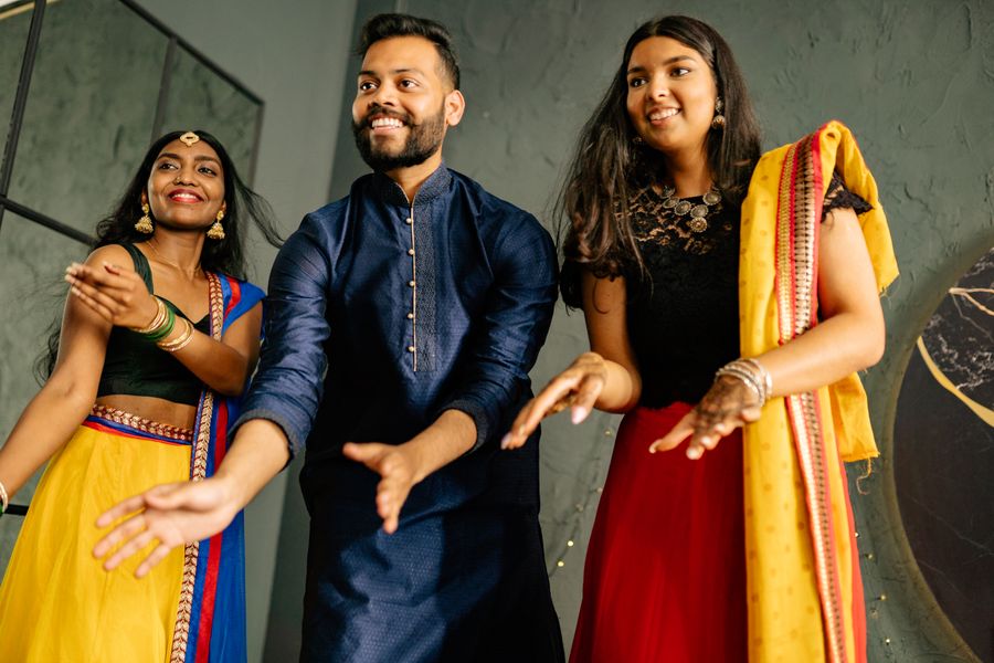A joyful group in colourful traditional outfits dancing together indoors