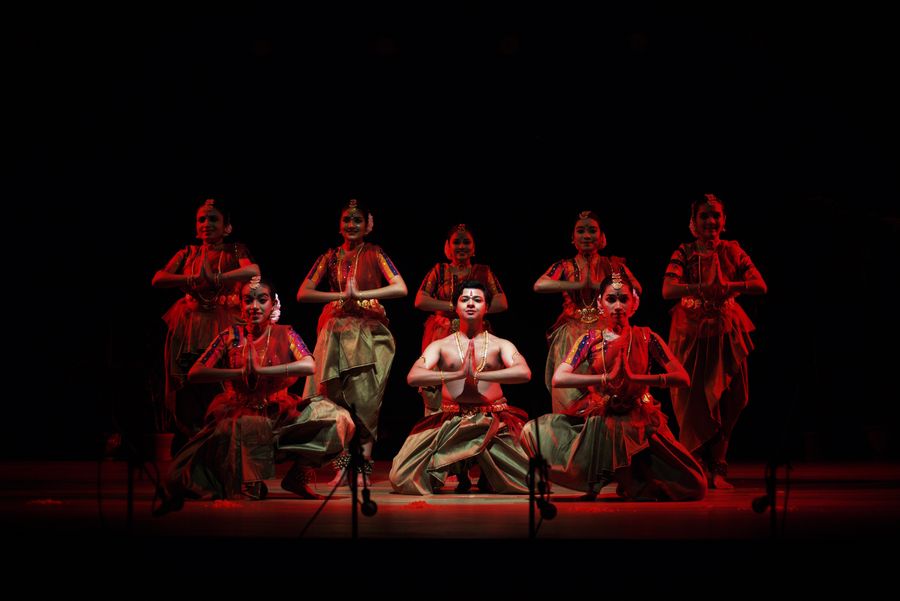 A dramatic classical dance performance under deep red stage lights