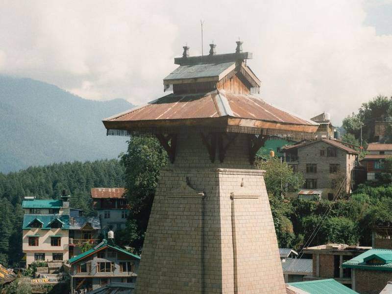 Wooden Himachali temple tower above the rooftops of Old Manali