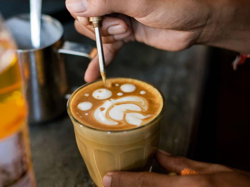 Barista's hands pouring steamed milk into a latte