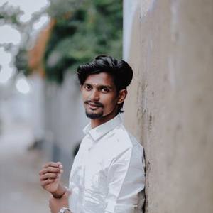 Young Indian man in a white shirt leaning against a wall