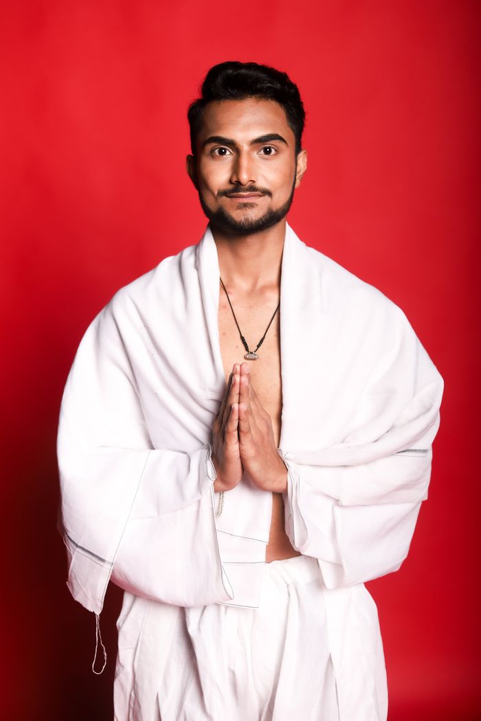 Yogi Devraj Bhatt in traditional white attire with hands folded in namaste