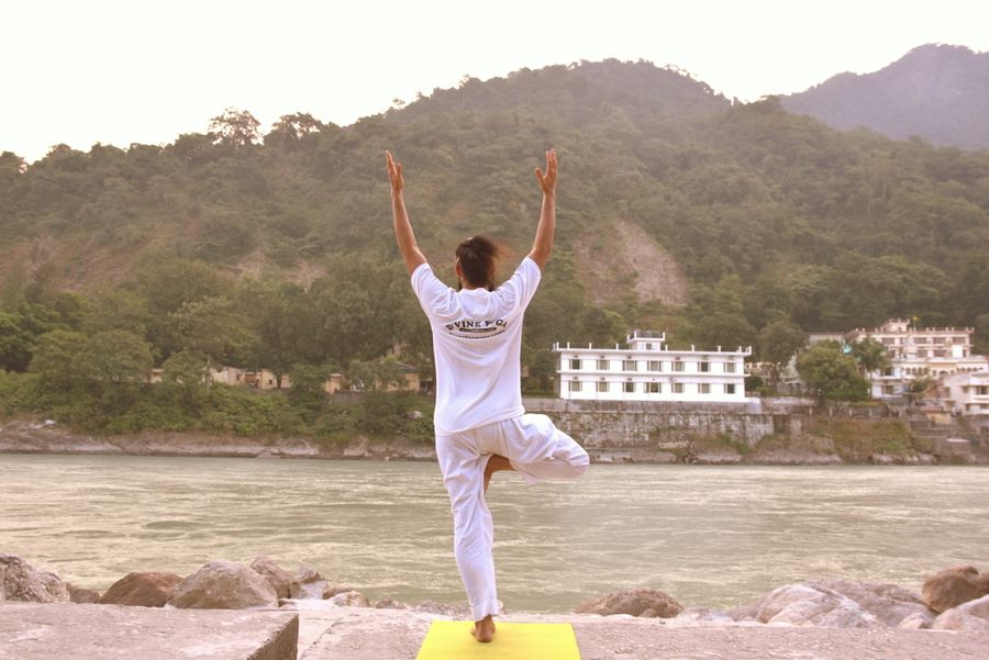 A practitioner in a yoga pose on the rocks beside the Ganga