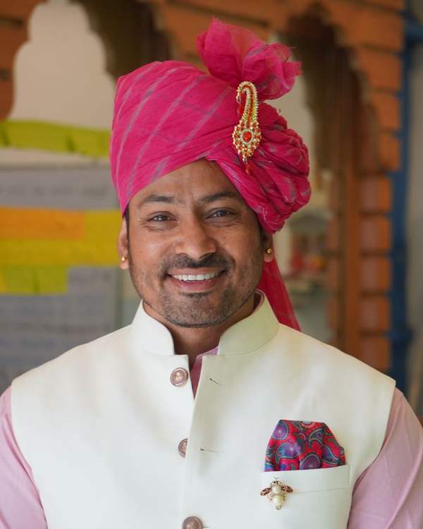 Smiling Indian man in a pink Rajasthani safa turban and white bandhgala
