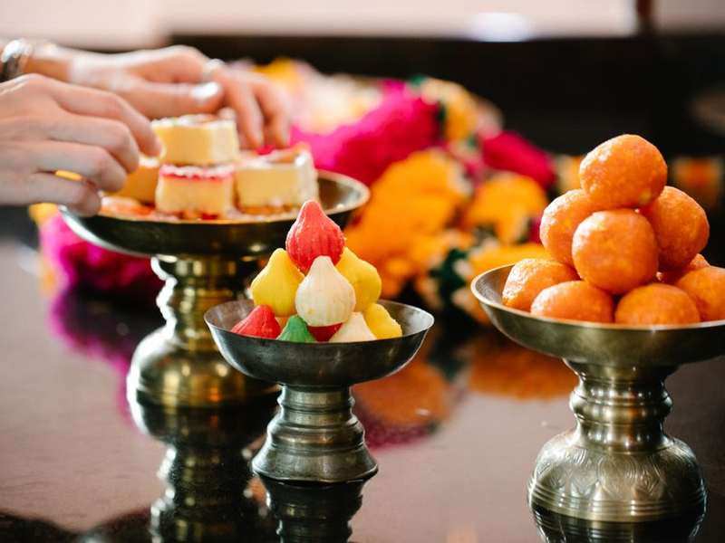 Brass stands of Indian sweets decorated with marigold garlands