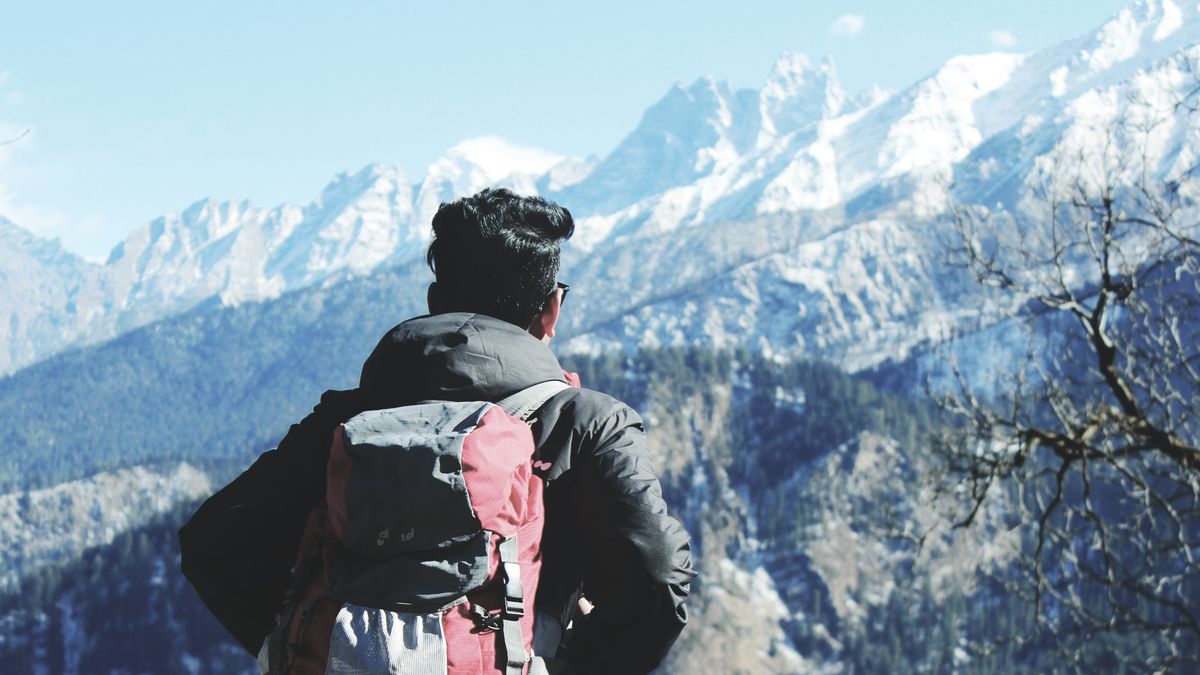 A traveller with a backpack gazing at snowy Himalayan peaks