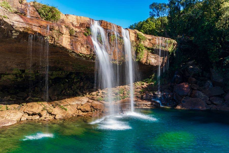 A waterfall pouring into a turquoise pool in the Meghalaya jungle