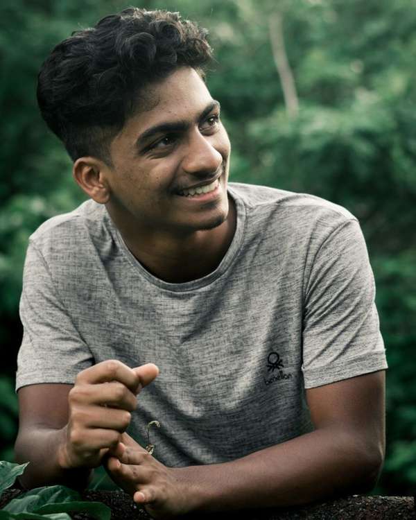 Young Indian man in a grey t-shirt smiling outdoors
