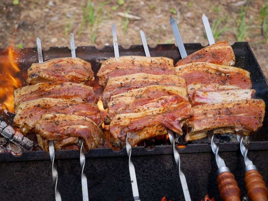 Pork skewers cooking over a charcoal grill