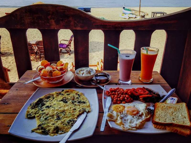Goan breakfast and drinks on a shack table overlooking the sea