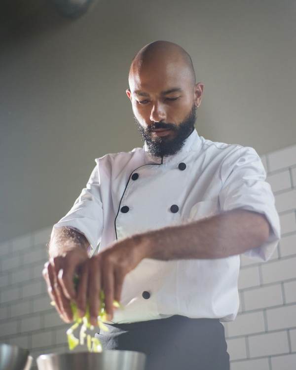 Indian chef in whites cooking at a stove