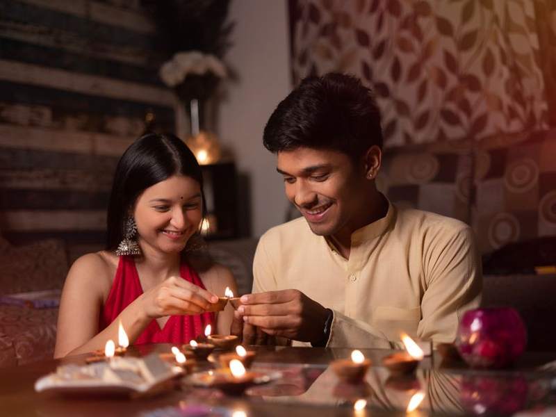 Young Indian couple lighting candles at a dinner table