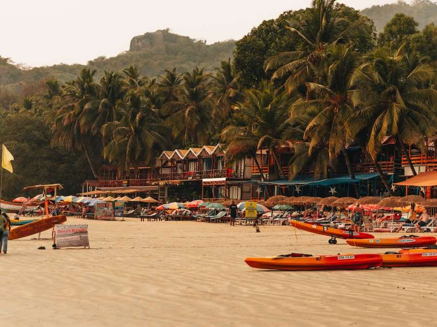 Fishing boats and kayaks pulled up on a palm-lined Goan beach
