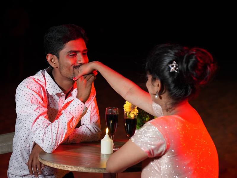 Indian couple sharing a candle-lit dinner in warm red light