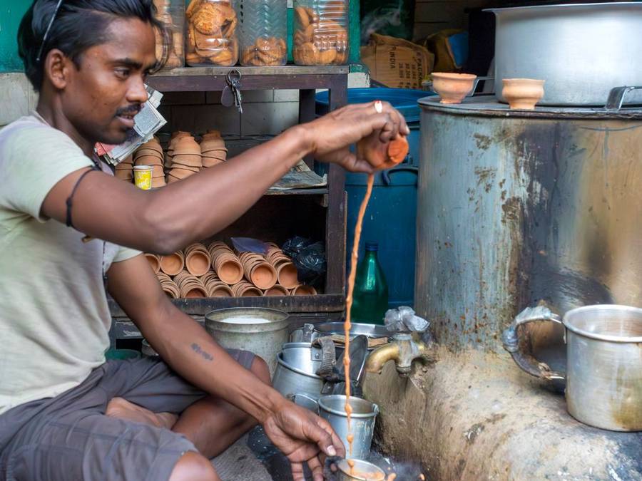 Chaiwala pouring tea at a busy street stall in Delhi