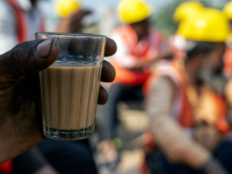 Hand holding a glass of chai on a Delhi street