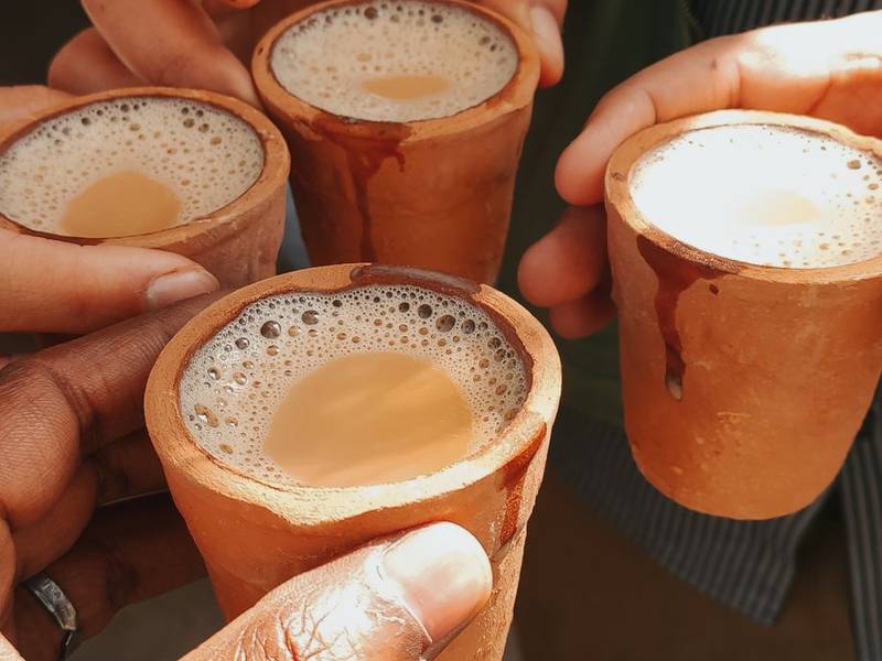 Friends clinking clay kulhads of chai together