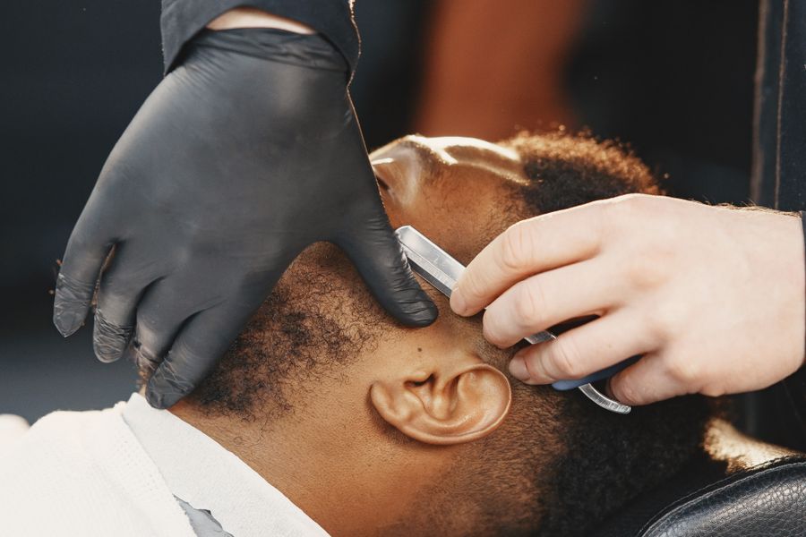 A barber shaving a customer with a straight razor
