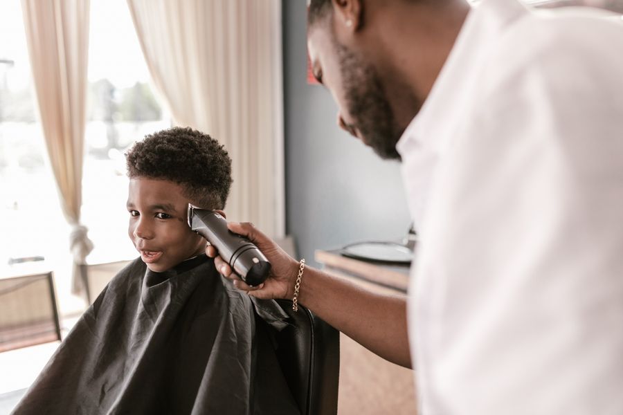 A young boy getting a haircut from a barber