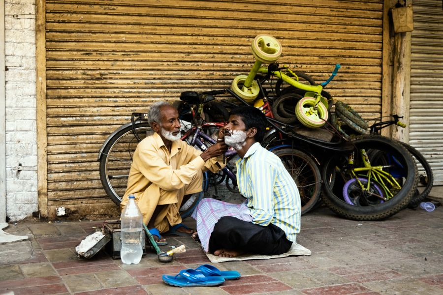 A street barber at work with his customer in the bazaar