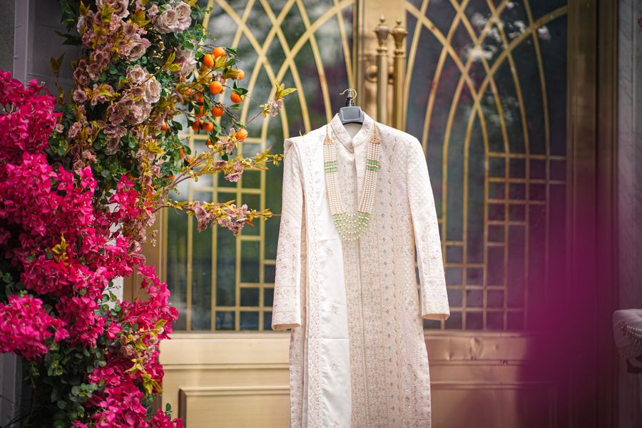 A wedding sherwani hanging amidst vibrant floral decorations