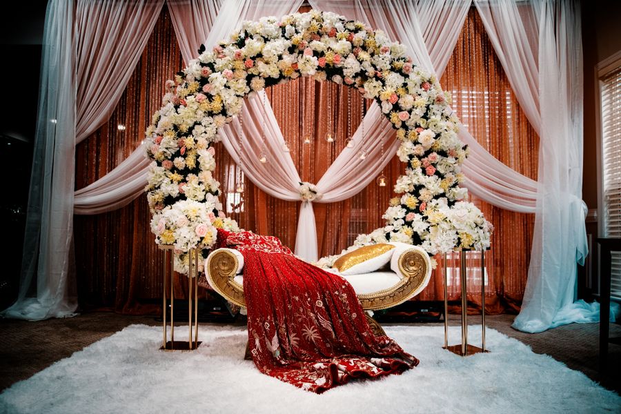 A luxurious wedding stage with a grand floral arch and traditional accents