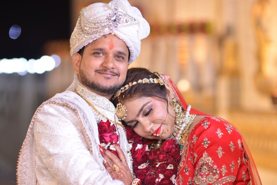 A joyful couple in rich traditional attire celebrating at their Indian wedding