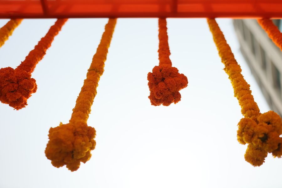 Marigold garlands strung against a clear sky before a ceremony