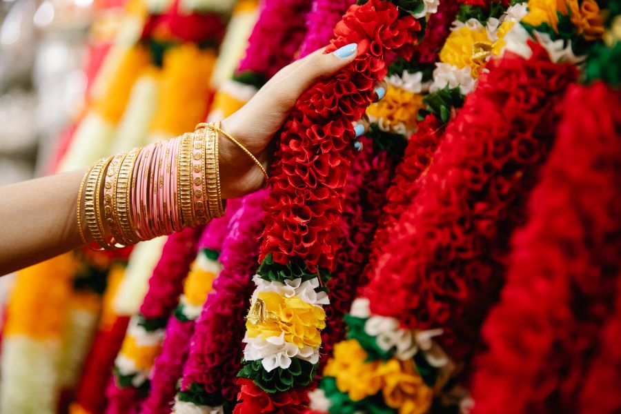 A henna-adorned hand holding fresh marigold welcome garlands