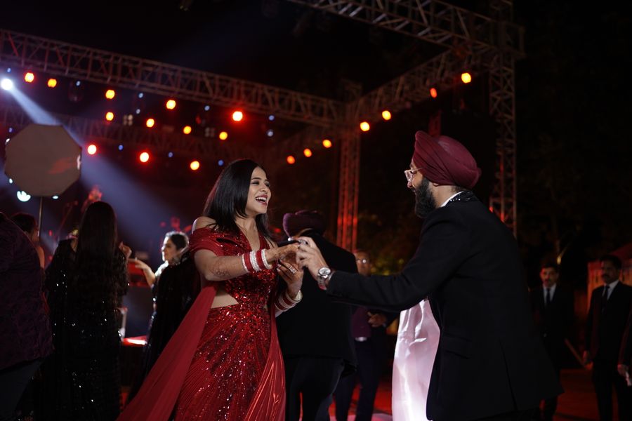 A couple dancing under glowing lights at a lively sangeet celebration