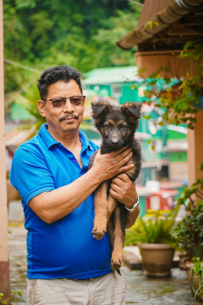 Aakash Rai holding a German Shepherd puppy in a garden