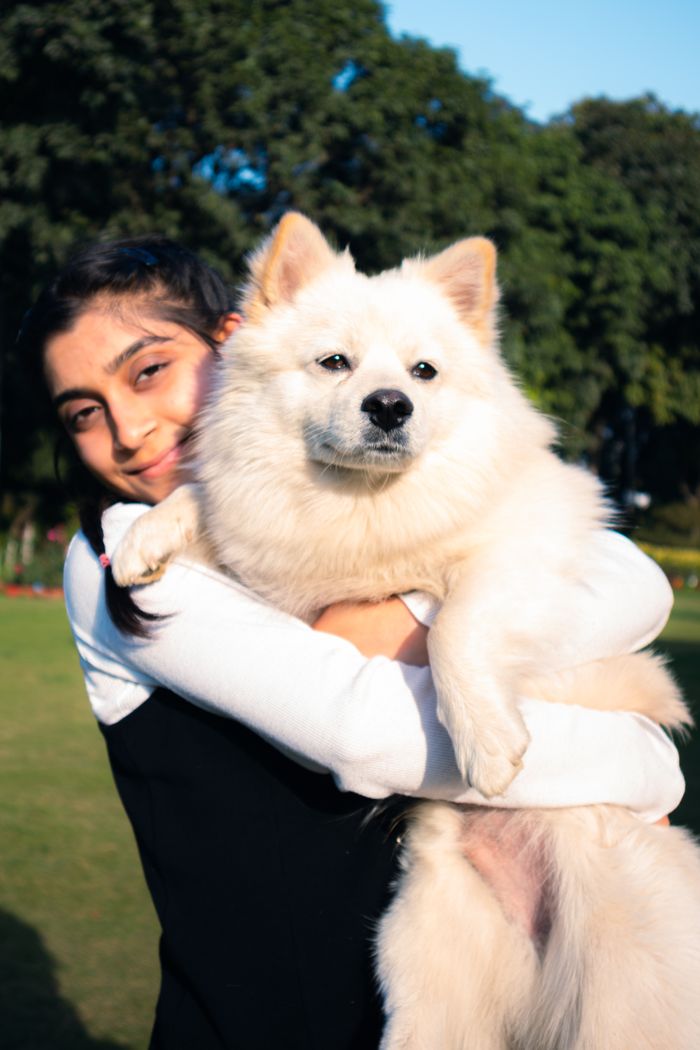 Sanika Deshpande smiling with a fluffy white Pomeranian