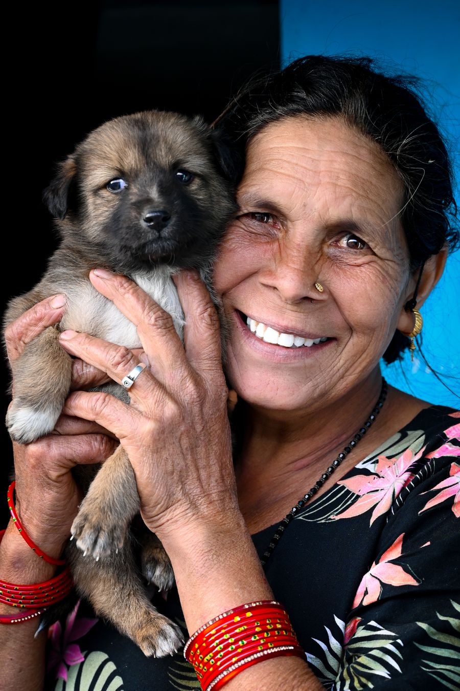 A senior woman joyfully cuddling a small puppy